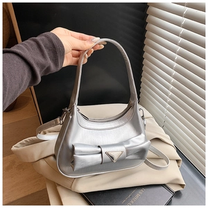 Detailed view of silver metallic handbag with bow accent and triangular metal plaque