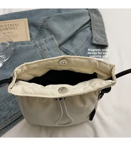 Detail view of the magnetic closure and drawstring on cream bucket shoulder bag