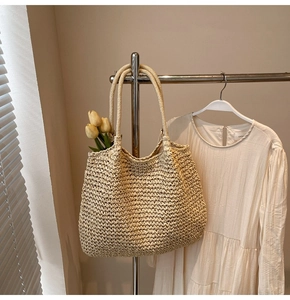 Détail d'un grand sac cabas en paille avec des tulipes suspendu sur un support minimaliste