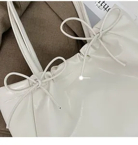 Gros plan d'un sac cabas en cuir souple crème avec détails plissés et nœuds élégants