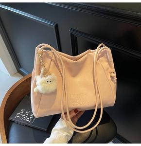 Detailed view of pink tote bag with embossed text and a cute furry monster charm