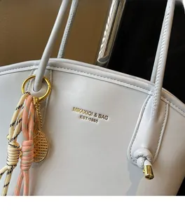 Dettaglio della borsa tote in pelle con finiture dorate e ciondolo da tennis