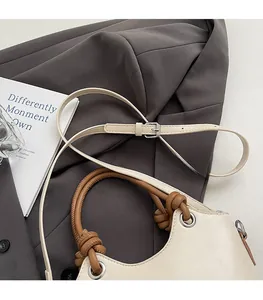 Détail de la bandoulière marron réglable avec boucle argentée sur un sac seau crème
