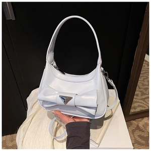 Detail of light blue bow handbag featuring a metallic finish and silver triangular plaque