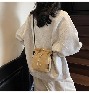 Detail of khaki drawstring bucket bag in nylon material with adjustable shoulder strap