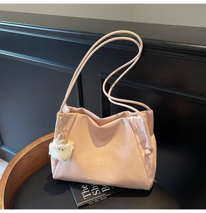Detailed close-up of pink tote bag featuring matte texture and plush doll charm