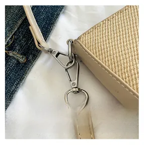 Close-up of beige woven texture with brown leather strap and silver metal lobster clasp