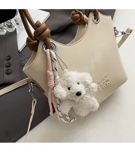 Détail du sac seau crème avec poignée nouée marron et breloque en peluche de chien