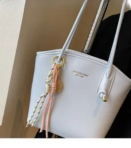 Dettaglio della borsa tote in ecopelle azzurra con logo dorato e ciondolo da tennis