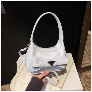 Detail showing bow decoration and metallic triangle logo on a sleek faux leather handbag