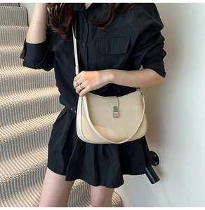 Detailed view of beige woven texture and silver buckle on the semi-round crossbody bag