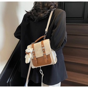 Detail of vintage beige and brown patchwork backpack with plush bear charm on model