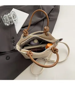 Intérieur spacieux du sac seau beige avec poignée tressée marron et accessoires divers