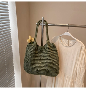 Détail du sac cabas tressé vert montrant la texture tricotée et les longues anses en paille