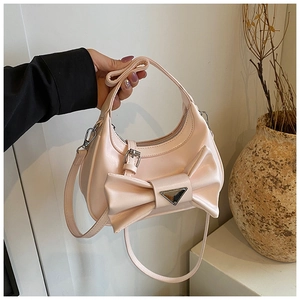 Close-up of pink handbag with decorative bow and triangular metal plaque detail