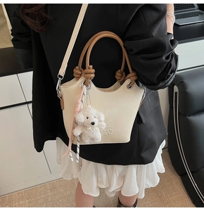 Détail du sac seau crème avec anses marron nouées et accessoire caniche en peluche doux