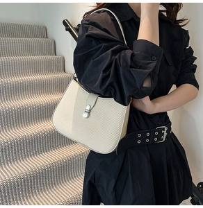 Detail of cream woven shoulder bag featuring a silver metal twist lock and leather strap