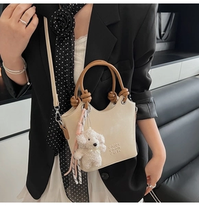 Détail du sac seau en PU beige avec poignée nouée marron et breloque chien en peluche