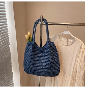 Détail du sac cabas tissé bleu foncé avec texture paille et anses rondes sur un cintre