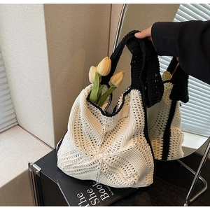Detail of white knit tote bag featuring black trim and textured wavy patterns
