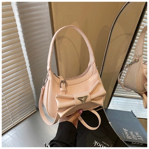 Close-up of a pink fashion handbag with a large decorative bow and a metallic accent