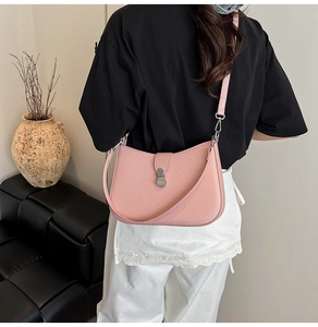 Close-up of pink woven shoulder bag with silver square buckle worn by a model