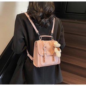 Detail of pink faux leather backpack with double strap buckles and a cute white bear charm