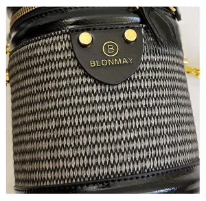 Dettaglio della trama del tessuto e del logo dorato su questa borsa a secchiello
