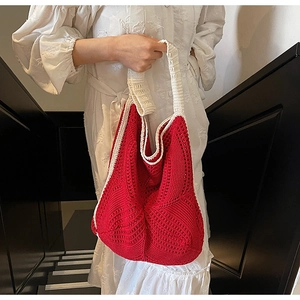 Detailed knit texture of a red crochet tote bag with wide cream shoulder straps
