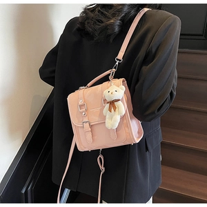 Detail of pink glossy leather backpack with silver buckles and a cute teddy bear charm