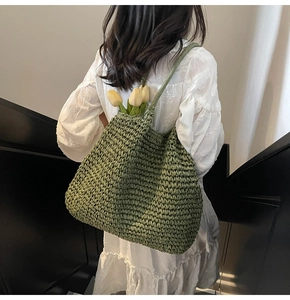 Gros plan d'un sac cabas en paille tissée verte avec texture artisanale et tulipes jaunes
