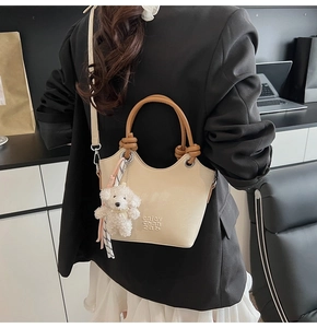 Détail du sac seau crème avec lettrage embossé et breloque en peluche pour chien