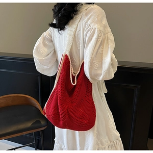 Detail of red hollow knit tote bag with cream straps shown on a model in white dress
