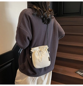 Close-up of cream drawstring bucket bag showing light nylon texture and cord strap