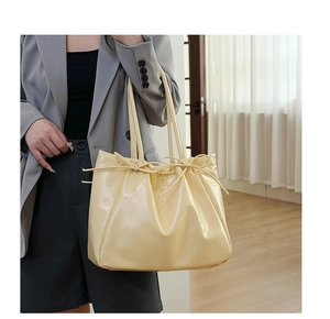 Détail du sac cabas en similicuir jaune pâle avec nœuds élégants et texture froncée