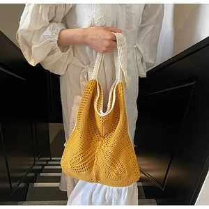 Detail of hand-knitted hollow crochet hobo bag in mustard yellow and beige patchwork