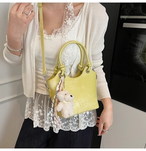 Détail du sac seau jaune avec anse nouée, breloque ours en peluche et foulard en soie