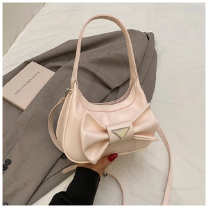 Close-up of pink bow handbag with matte leather texture and golden metal logo plaque