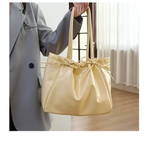 Détail du grand sac cabas crème avec cordons à nœuds et texture en cuir brillant