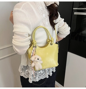 Détail du sac seau jaune avec pendentif chien en peluche et foulard en soie sur la bandoulière