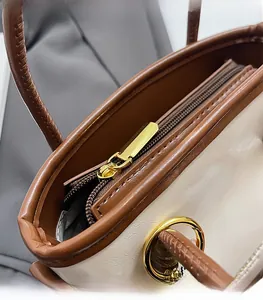 Detailed close-up of smooth gold-tone zipper and contrast stitching on the bucket bag