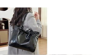 Détail du grand sac cabas noir brillant avec cordon de serrage sur blazer gris