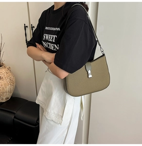 Detail showing the olive green woven texture and silver metal buckle of the shoulder bag