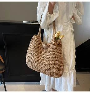 Détail d'un sac cabas en paille tressée avec texture naturelle et grand design style hobo