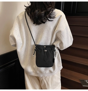 Close-up of black drawstring crossbody phone bag in high-density nylon material