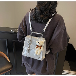 Detail of silver metallic mini backpack with marble texture and plush bear charm