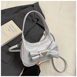 Detail of light blue crossbody bag with oversized bow and metallic triangle hardware