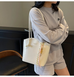 Dettaglio della borsa tote in pelle bianca con nappa in corda intrecciata e logo dorato