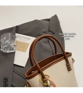 Detail of rounded top handle on off-white bucket bag with contrast stitching