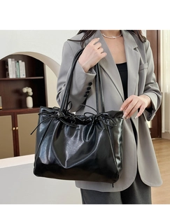 Vue détaillée du grand sac cabas noir en cuir brillant avec un nœud décoratif élégant